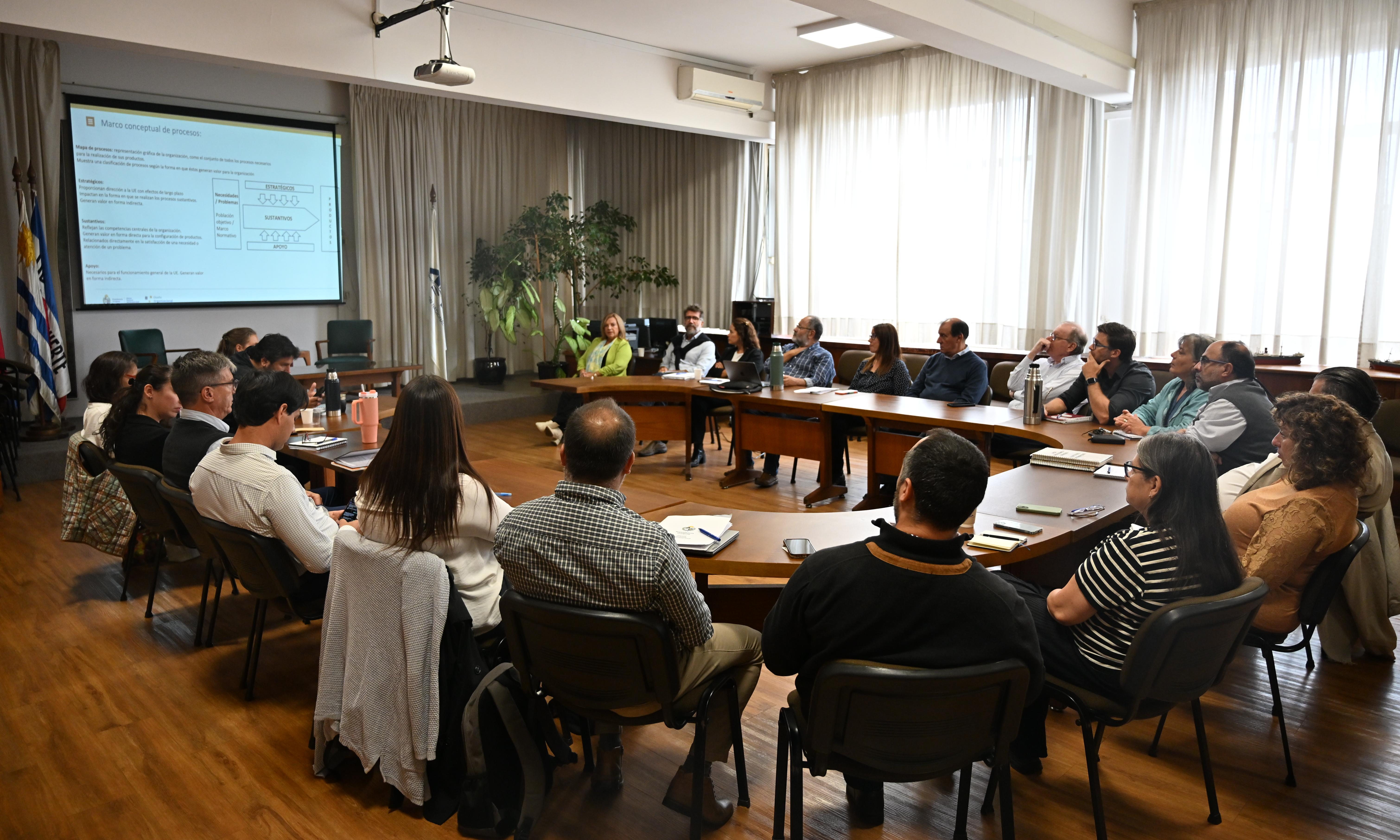 personas sentadas alrededor de una mesa con pantalla a la izquierda