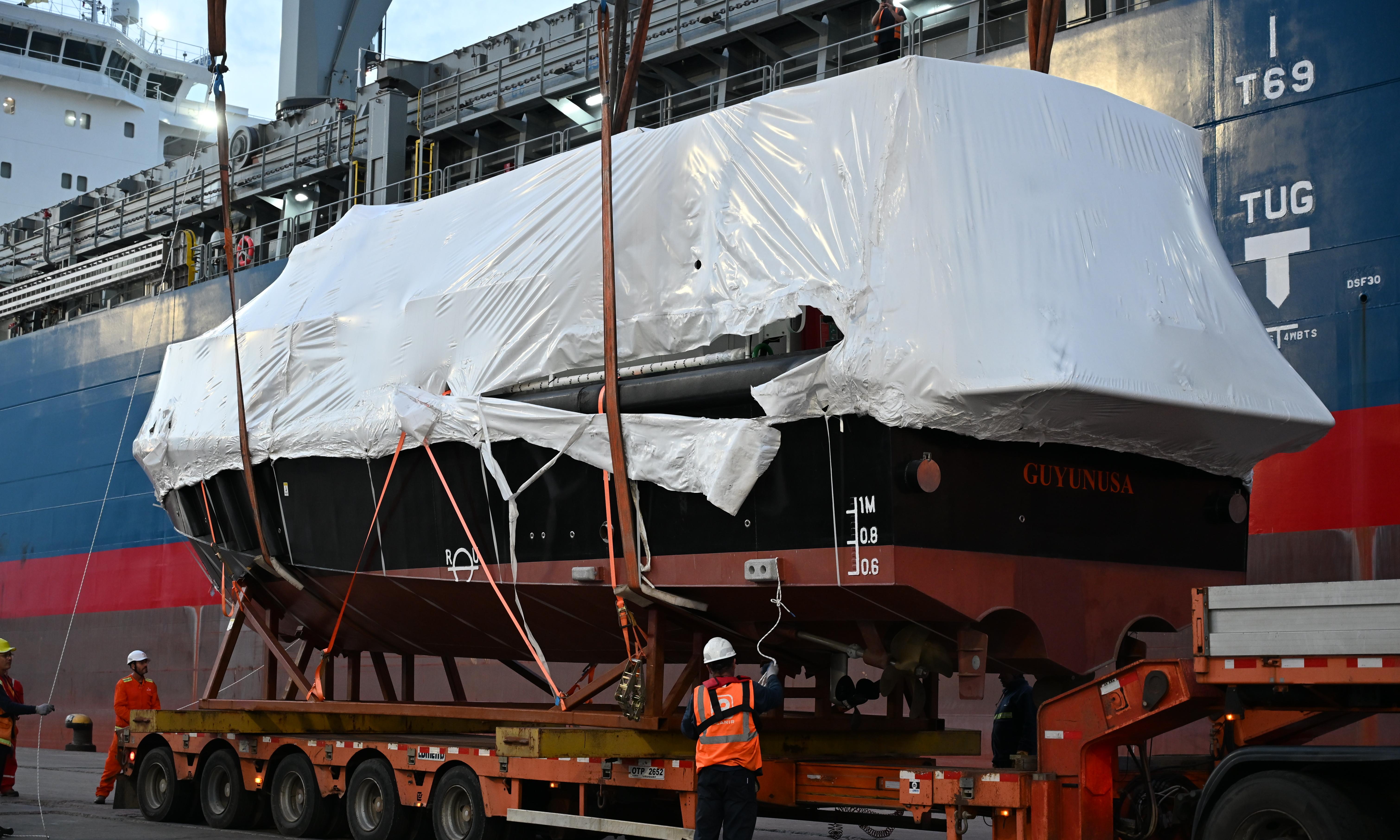 Maniobra con Lancha atada con cabos bajando desde un barco hacia camión